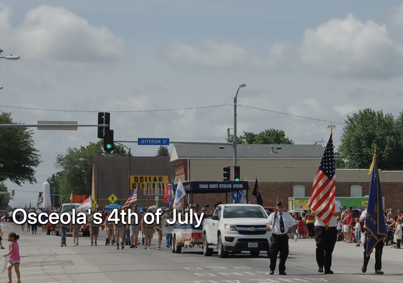 Street view of parade with color guard, truck, and people